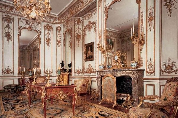 Unique carved handmade Rococo style furniture in spacious high room with fireplace and a huge mirror